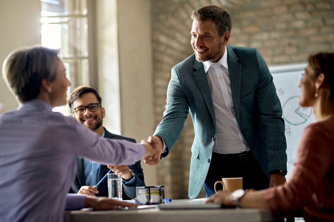 business coworkers shaking hands meeting office focus is businessman