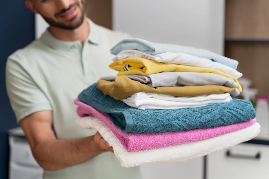 man holding pile clean clothes
