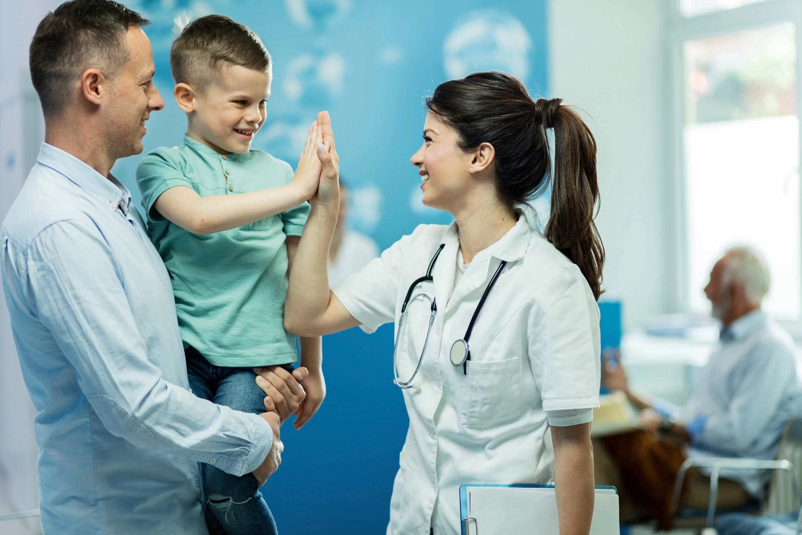 happy female doctor giving high fie little boy who came with father hospital scaled